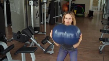 Spor salonunda ağırlık çalışan genç bir kadın..