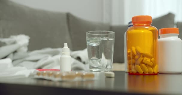 錠剤や錠剤の多くのボトルを閉じ 自宅でテーブルの上に水のガラス — ストック動画