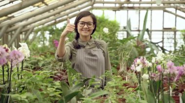 Serada baş parmağını gösteren genç bir bahçıvan kadın portresi..