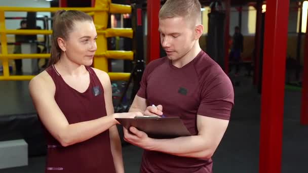 Muscular Personal Coach Writing Clipboard Talking Young Woman Cross Training — Stock Video