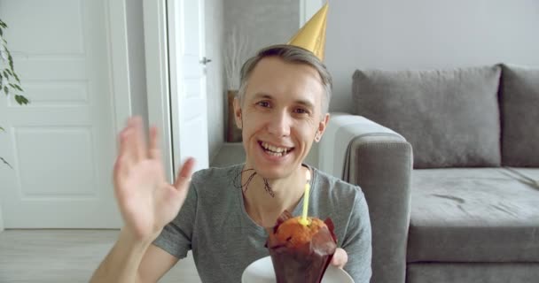 幸せな若い男の肖像は オンライン通信を楽しんでいるか 誕生日を祝うビデオを記録し 自宅でケーキの上にろうそくを吹いて — ストック動画