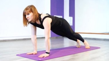 Genç bir kadın spor salonundaki paspasın üzerinde egzersiz yapıyor.