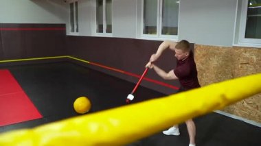 Güçlü kaslı adam spor salonundaki lastiğe balyozla vuruyor..