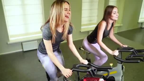 Two Young Smiling Women Cycling Machines Doing Cardio Training Together — Stock Video