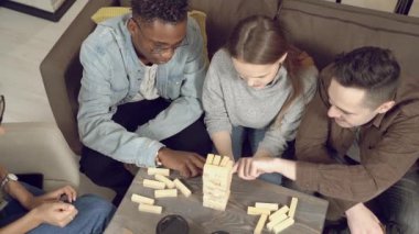Bir grup çok ırklı mutlu arkadaş blok kaldırma oyunu oynuyor ve evde birlikte eğleniyorlar..