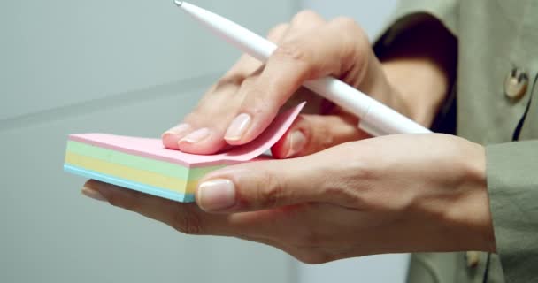 メモやメモを作るためにピンクのステッカーを引き裂く女性の手の閉鎖 — ストック動画