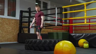 Spor salonunda lastiğe balyozla vuran bir adam. Crossfit