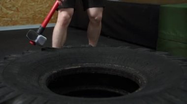 Spor salonunda lastiğe balyozla vuran bir adam.