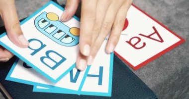 Kadın ellerinin alfabeyi öğrenmek için çok renkli kartlar, harfler ve resimlerle yakın plan çekimleri. Okul öncesi eğitim ya da İngilizce öğrenme.