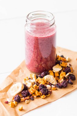 Kurutulmuş kiraz, muz, elma, yaban mersini bir highball cam beyaz zemin üzerine güler yüzlü. Kurutulmuş meyve güler yüzlü