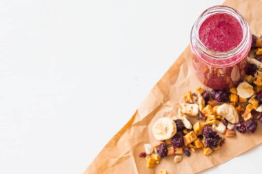 Kurutulmuş kiraz, muz, elma, yaban mersini bir highball cam beyaz zemin üzerine güler yüzlü. Kurutulmuş meyve güler yüzlü