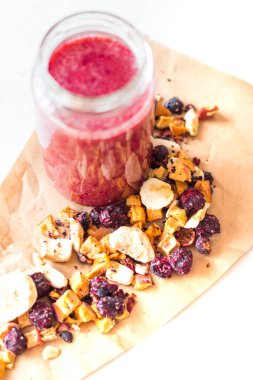 Kurutulmuş kiraz, muz, elma, yaban mersini bir highball cam beyaz zemin üzerine güler yüzlü. Kurutulmuş meyve güler yüzlü