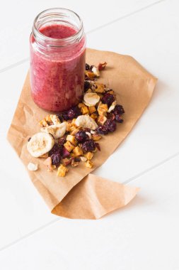 Kurutulmuş kiraz, muz, elma, yaban mersini bir highball cam beyaz zemin üzerine güler yüzlü. Kurutulmuş meyve güler yüzlü