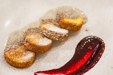 Peynirli kek, taze reçel ve haşhaş tohumu sosu. Süzme peynirli krep ya da kremalı börek tabağa yakın duran pudra şekerli. Sağlıklı ve diyet kahvaltı.