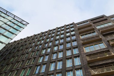 Amsterdam, Hollanda - 28 Kasım 2019: Mavi gökyüzüne karşı yeni modern kahverengi binaya bakış açısı