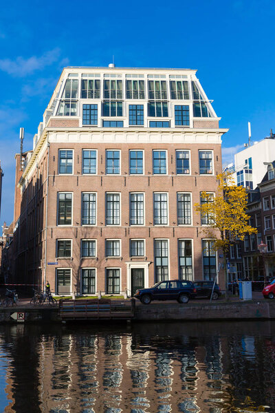 Amsterdam, Netherlands - November 28, 2019: Traditional one alone dutch building on canal in Amsterdam