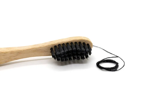 Black dental floss and bamboo toothbrush on a white background. — 스톡 사진