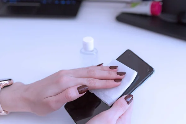 Akıllı telefonun Coronavirus Covid-19 'dan nasıl temizlenip sterilize edileceğini. Akıllı telefonunu temizleyen bir kadın.