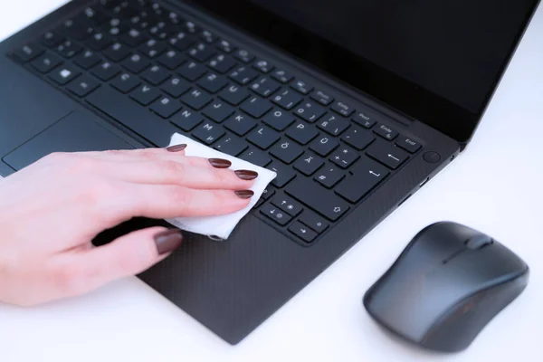 female hand disinfects the keyboard and mouse with a napkin with antibacterial gel