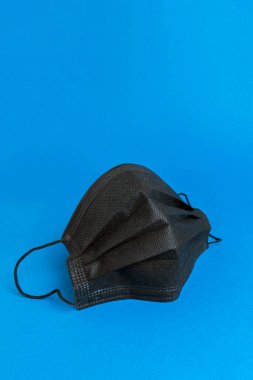 Mavi arka planda siyah tıbbi maske. Kapat.