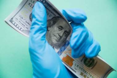 Koruyucu eldivenin içinde dolar var. Coronavirus konsepti yüzünden ABD 'deki finansal kriz. Benjamin Franklins 'in gözlerine odaklan.