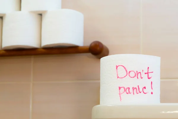 Не паникуй на туалетной бумаге. Рулон туалетной бумаги на фоне нескольких рулонов . — стоковое фото