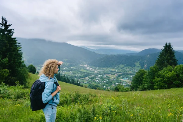 Een jong meisje staat bovenop een berg in bewolkt weer genieten van het uitzicht — Stockfoto