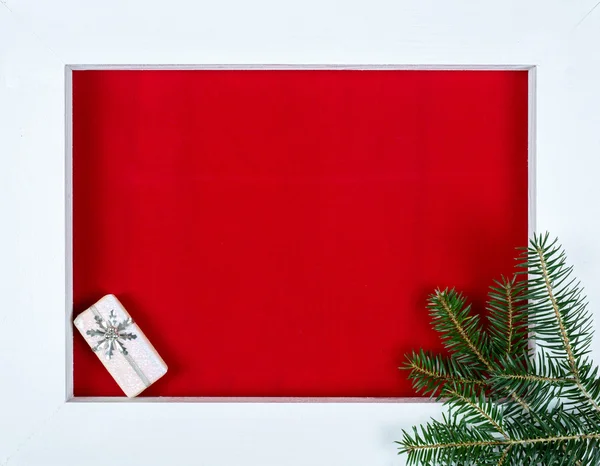 White wooden frame and a christmas gift over a red background — Stock Photo, Image