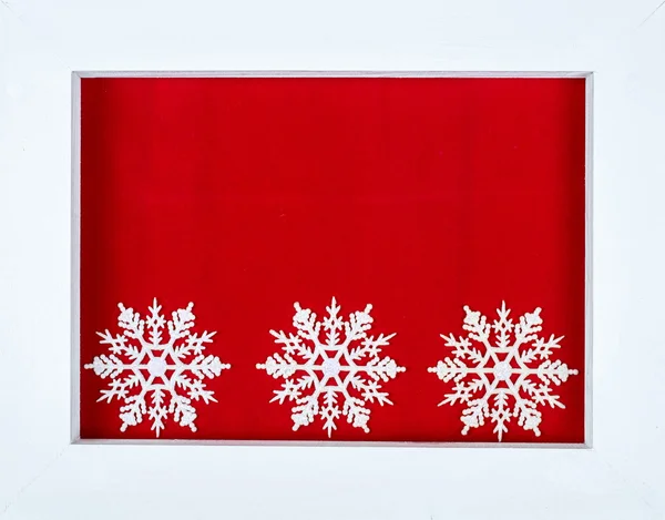 White wooden frame and snowflakes over a red background — Stock Photo, Image