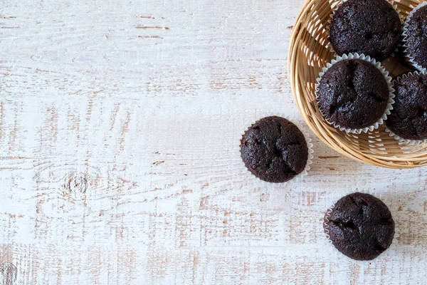 Magdalenas de chocolate en una mesa de madera rústica blanca - enfoque selectivo, espacio para copiar —  Fotos de Stock