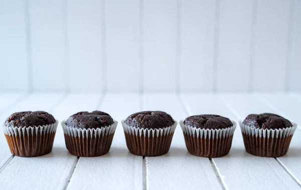 Magdalenas de chocolate en una mesa de madera rústica blanca - enfoque selectivo, espacio para copiar —  Fotos de Stock