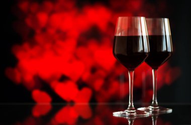 İki bardak kırmızı şarap sparkles ve gül bokeh arka plan karşı. Çok sığ derinlik-in tarla. Seçici odak, kopya alanı