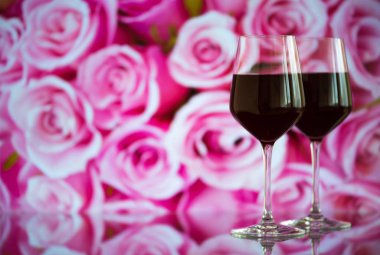 İki bardak kırmızı şarap sparkles ve gül bokeh arka plan karşı. Çok sığ derinlik-in tarla. Seçici odak, kopya alanı