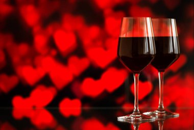 İki bardak kırmızı şarap sparkles ve gül bokeh arka plan karşı. Çok sığ derinlik-in tarla. Seçici odak, kopya alanı