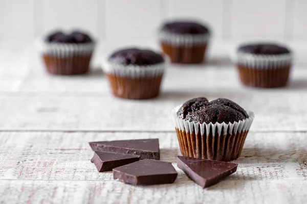 Magdalenas de chocolate en una mesa de madera rústica blanca - enfoque selectivo, espacio para copiar —  Fotos de Stock