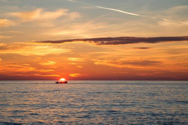 Balıkçı teknesi arka planda inanılmaz altın gündoğumu, bulutlar ve yükselen güneş.