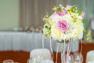 Çok güzel bir restoranda bir masada çiçek dekorasyon düğün. Beyaz masa örtüleri, parlak Oda.