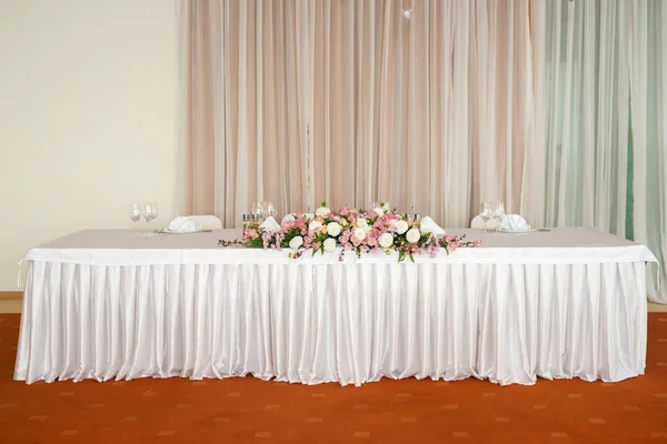 Gyönyörű esküvői virág dekoráció, egy asztal, egy étteremben. Fehér abrosz, világos szoba. — Stock Fotó