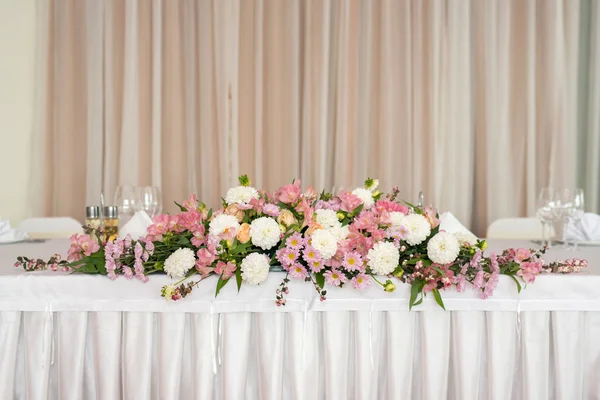 Красивые свадебные цветочные украшения на столе в ресторане.Белые скатерти, светлая комната . — стоковое фото