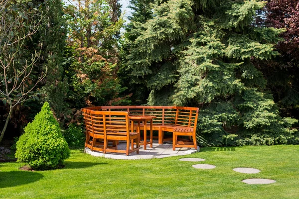 Día soleado en un jardín de primavera con mesa de madera y bancos —  Fotos de Stock