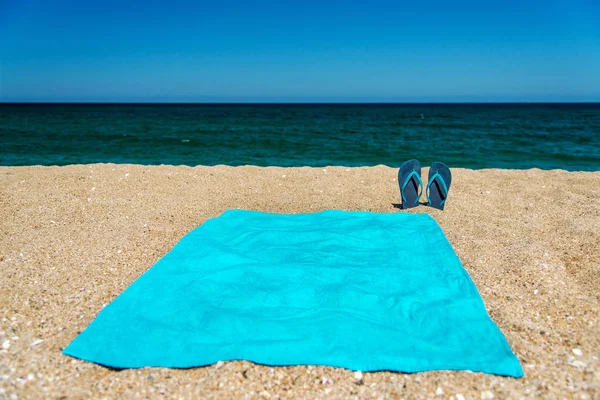 Blue sandal flip flop and towel on yellow sand. Summer fun time and accessories on the beach, summer vacations — Stock Photo, Image