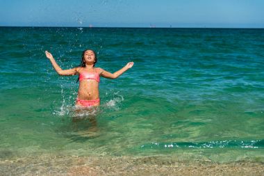Kız denize yüzme ve su sıçramasına eğleniyor