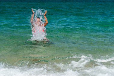 Kız denize yüzme ve su sıçramasına eğleniyor