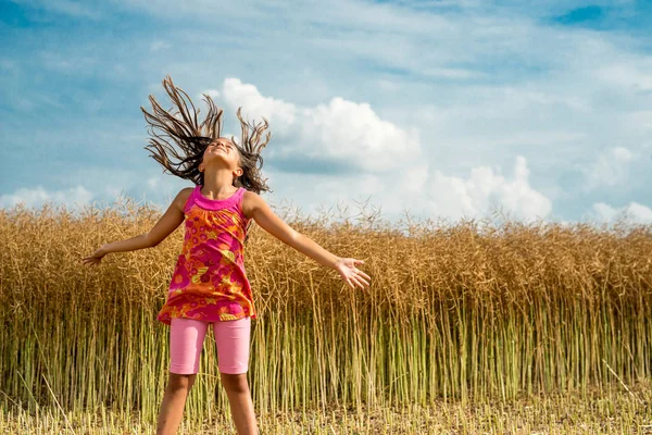 Happy little girl in a field of ripe rapeseed — Stock Photo, Image