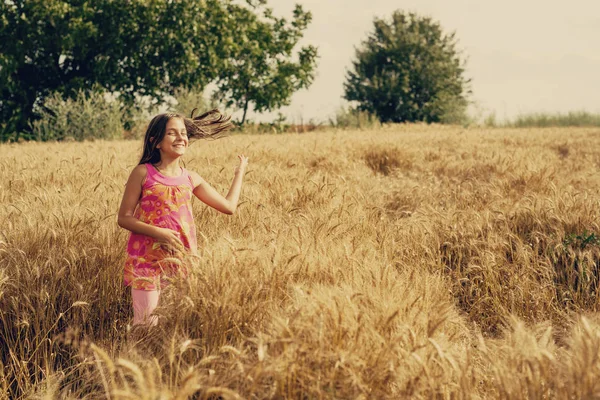 Happy little girl in a field of ripe wheat — Stock Photo, Image