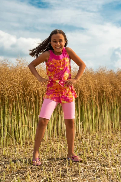 Happy little girl in a field of ripe rapeseed - vertical orientation — Stock Photo, Image