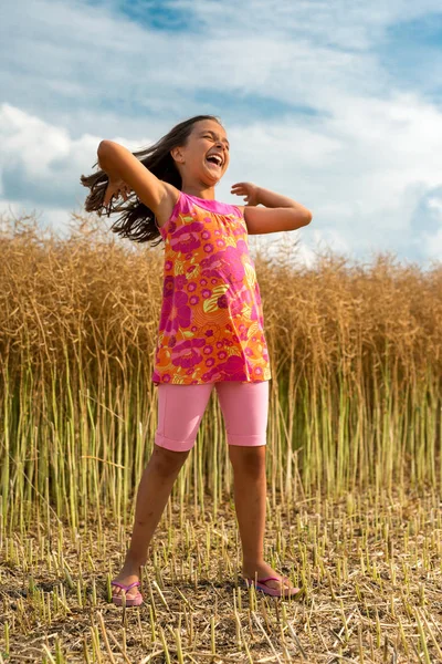 快乐的小女孩在成熟的油菜籽-垂直方向的领域 — 图库照片