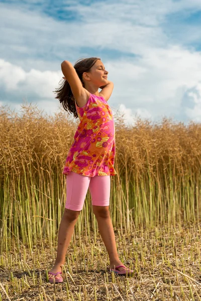 Happy little girl in a field of ripe rapeseed — Stock Photo, Image