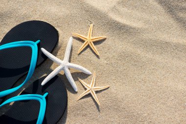 Summer vacation concept starfish and flip flops on sandy tropical beach - selective focus, top view, copy space