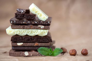 Fındık kakao tozu ve nane içeren farklı çikolata çeşitleri. Seçici odak, kahverengi kağıt kaplama arka plan.